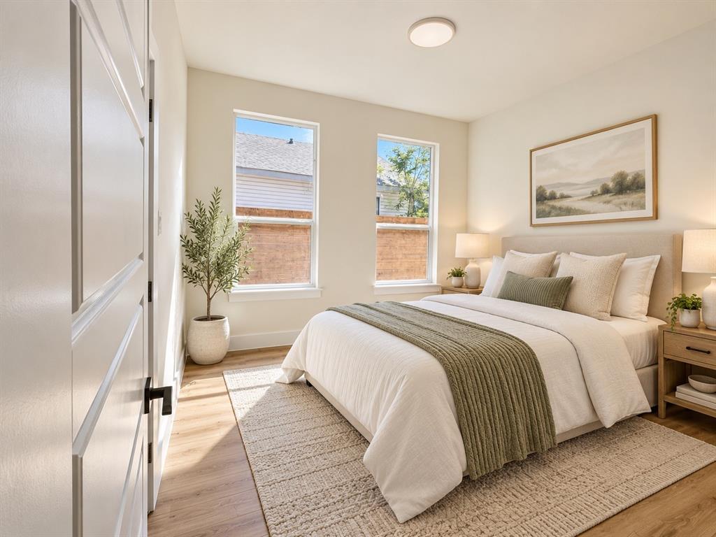 Bedroom featuring wood-finish flooring, dual windows with natural light, and a minimalist flush-mount ceiling light fixture