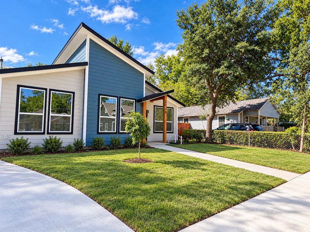 Modern architectural exterior featuring mixed-material horizontal siding, a mono-pitch roofline, expansive multi-pane windows with dark trim, and an exposed timber entryway support