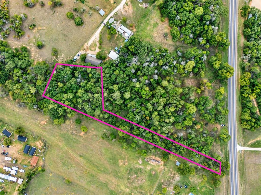 Aerial perspective of land parcel featuring dense mature tree coverage, expansive acreage, and direct road access