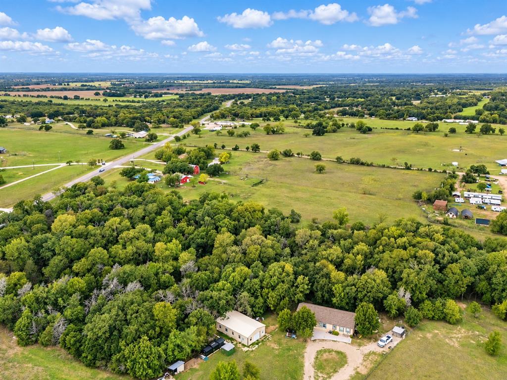 Expansive acreage featuring mature tree clusters, cleared pasture land, a detached workshop, and a multi-section residence