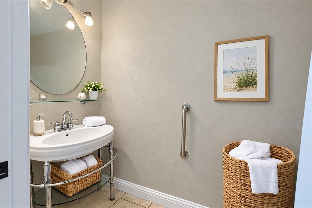 Console sink with a chrome frame, oval basin, glass shelf, wall-mounted oval mirror, and installed grab bar
