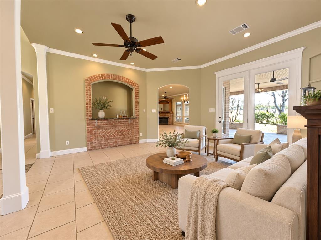 Living area featuring tile flooring, recessed lighting, a ceiling fan, a brick-surround built-in alcove, and multi-pane glass doors