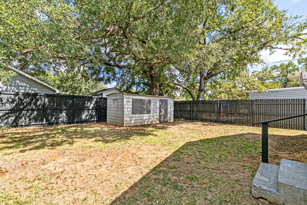 Spacious, fenced backyard with mature shade trees and a convenient storage shed.