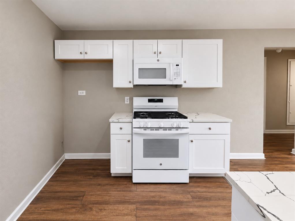 Additional kitchen view highlighting white cabinetry, gas range, and microwave. Additional kitchen view highlighting white cabinetry, gas range, and microwave.