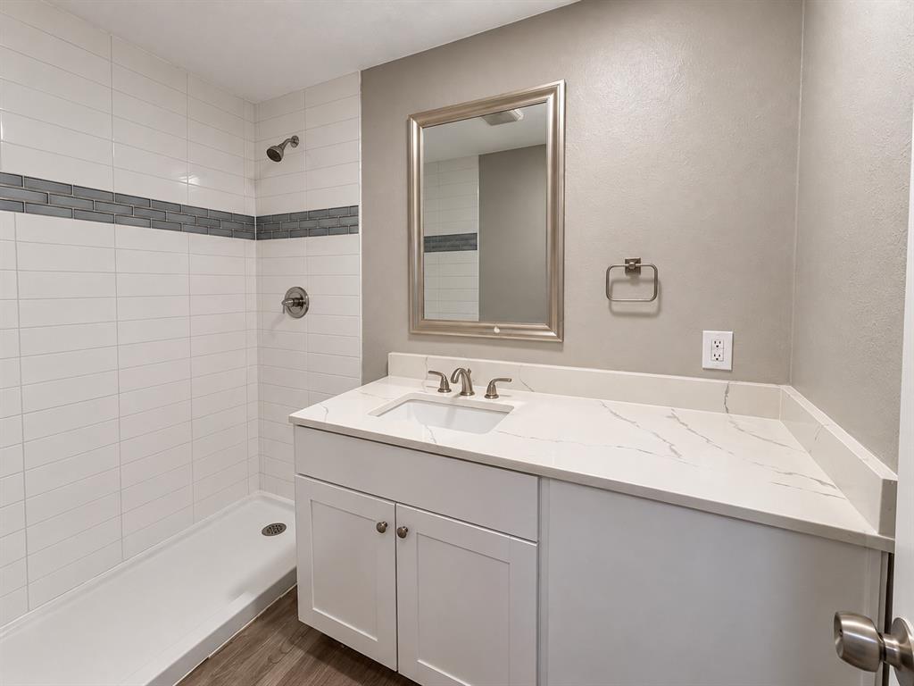 Updated bathroom featuring a spacious vanity, modern countertop, and tiled shower.