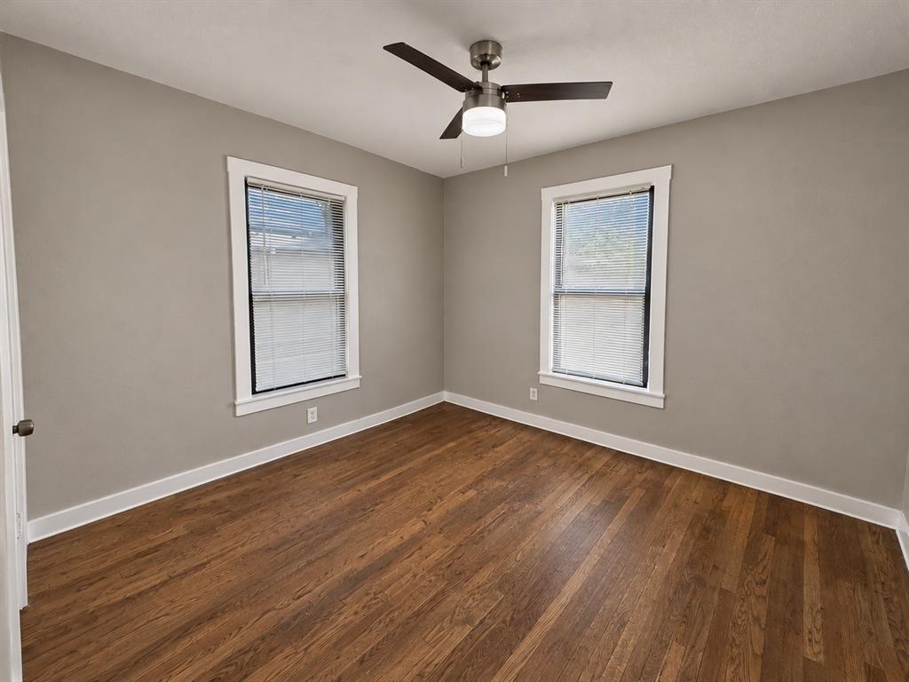 Bright bedroom featuring two windows, wood flooring, and a ceiling fan.
