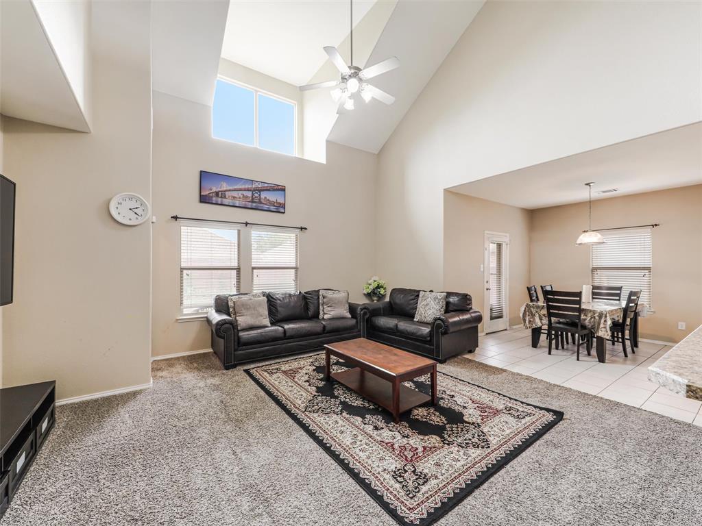 Vaulted ceilings, expansive windows, overhead lighting fixture, tiled flooring, and carpeted flooring