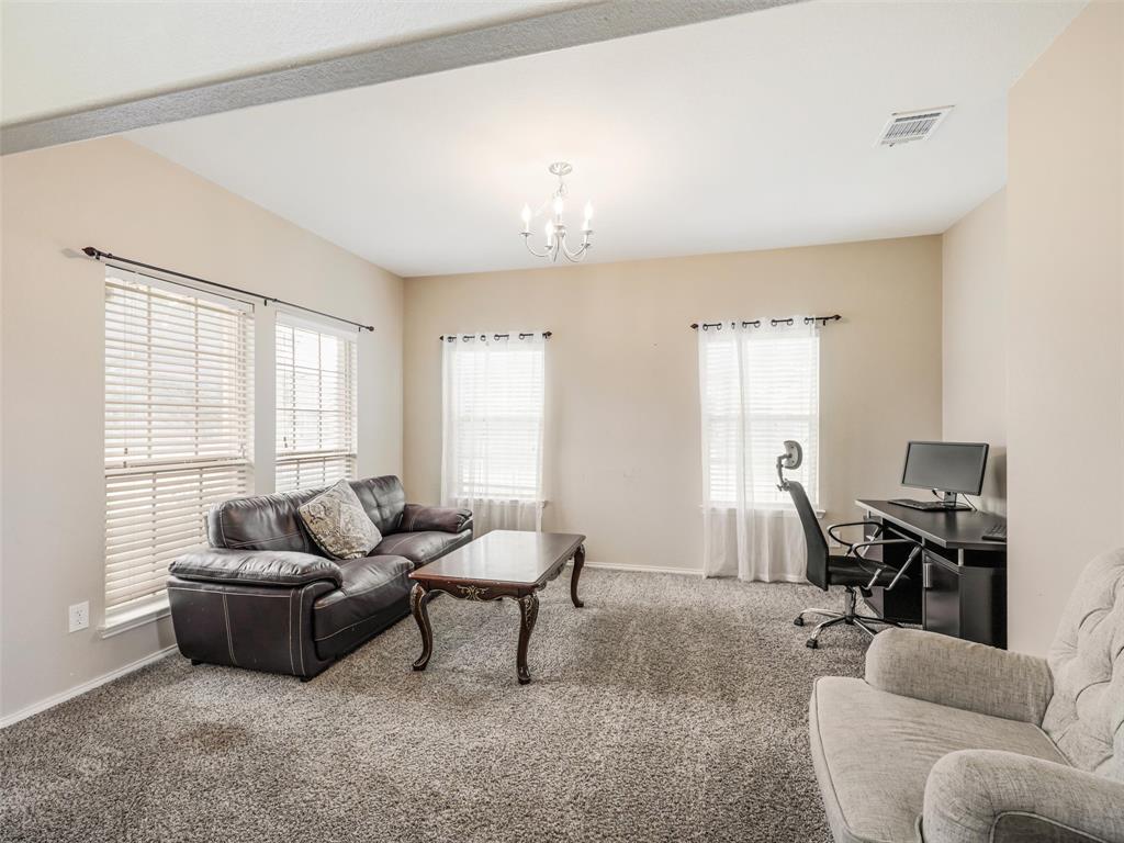 Living area featuring wall-to-wall carpeting, multiple windows with neutral blinds, and an overhead chandelier