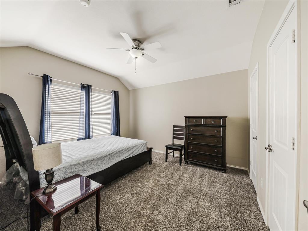 Vaulted ceiling, neutral wall tones, multi-textured carpeting, and a ceiling-mounted light fixture with integrated fan