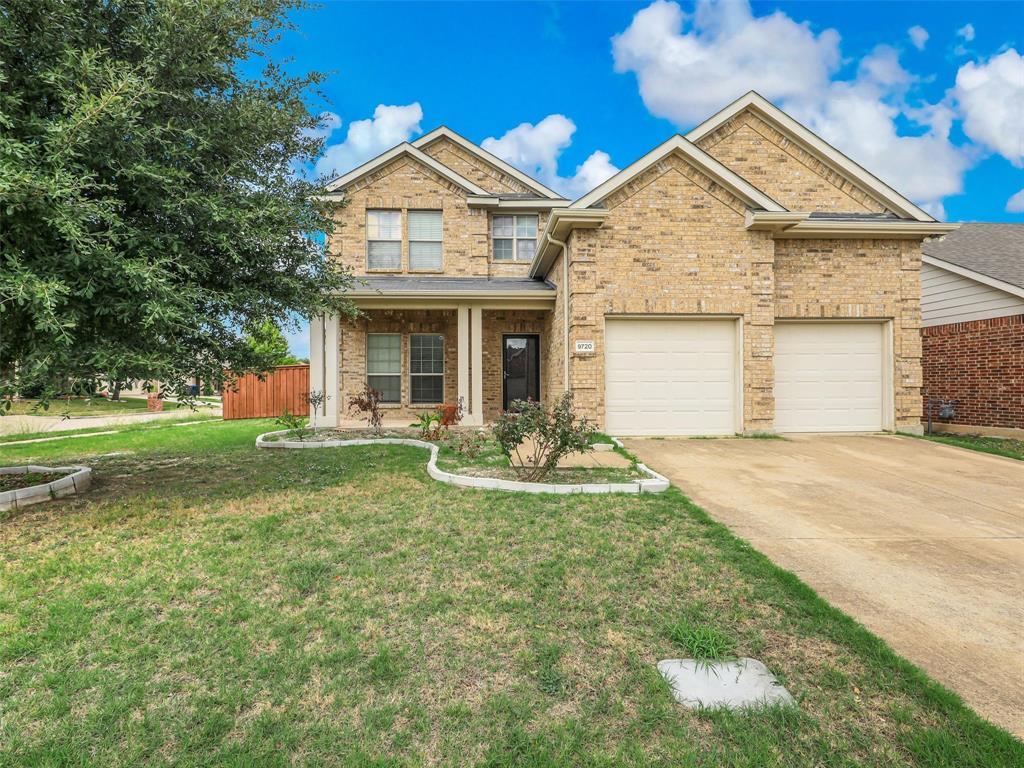 Two-story brick exterior featuring a multi-gabled roofline, concrete driveway, and attached two-car garage
