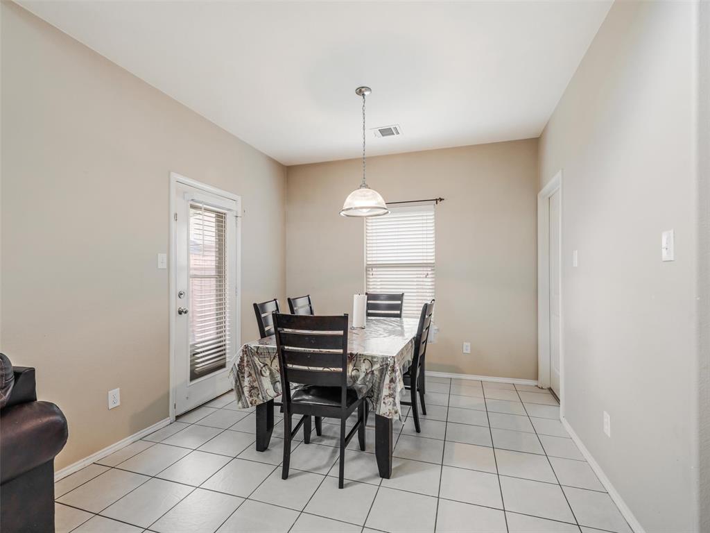 Dining area featuring large-format ceramic tile flooring, a brushed-nickel pendant light fixture, and a glass-paneled exterior door