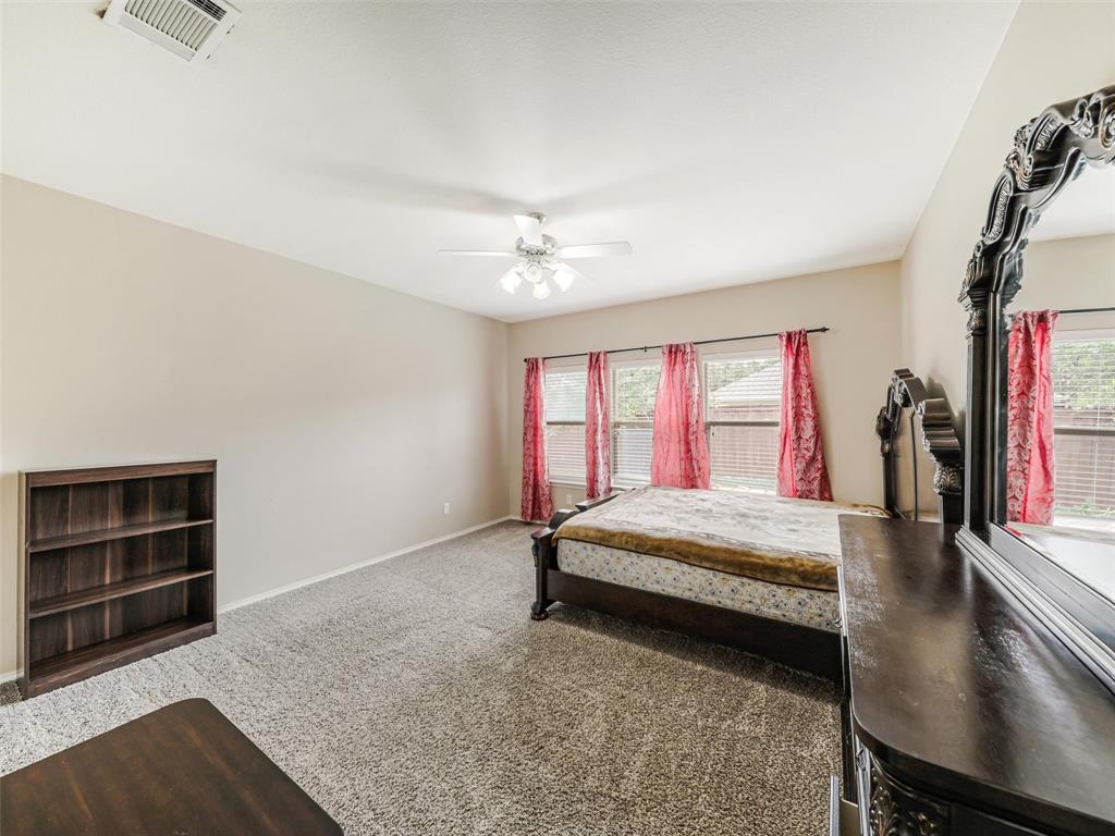 Neutral-toned room featuring wall-to-wall carpeting, multiple windows with natural lighting, and a ceiling-mounted light fixture with a fan