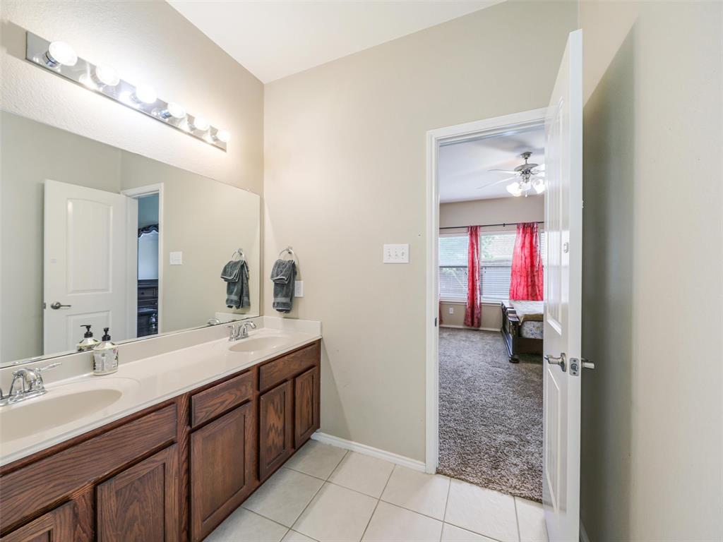 Double vanity featuring wood cabinetry, integrated sinks, solid surface countertops, a full-width mirror, and multi-bulb wall lighting