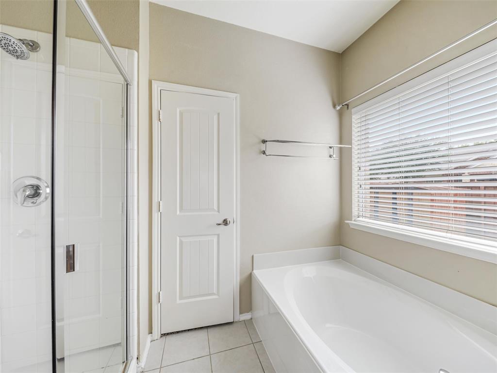 Walk-in shower with chrome hardware, soaking tub with tile surround, and horizontal window blinds