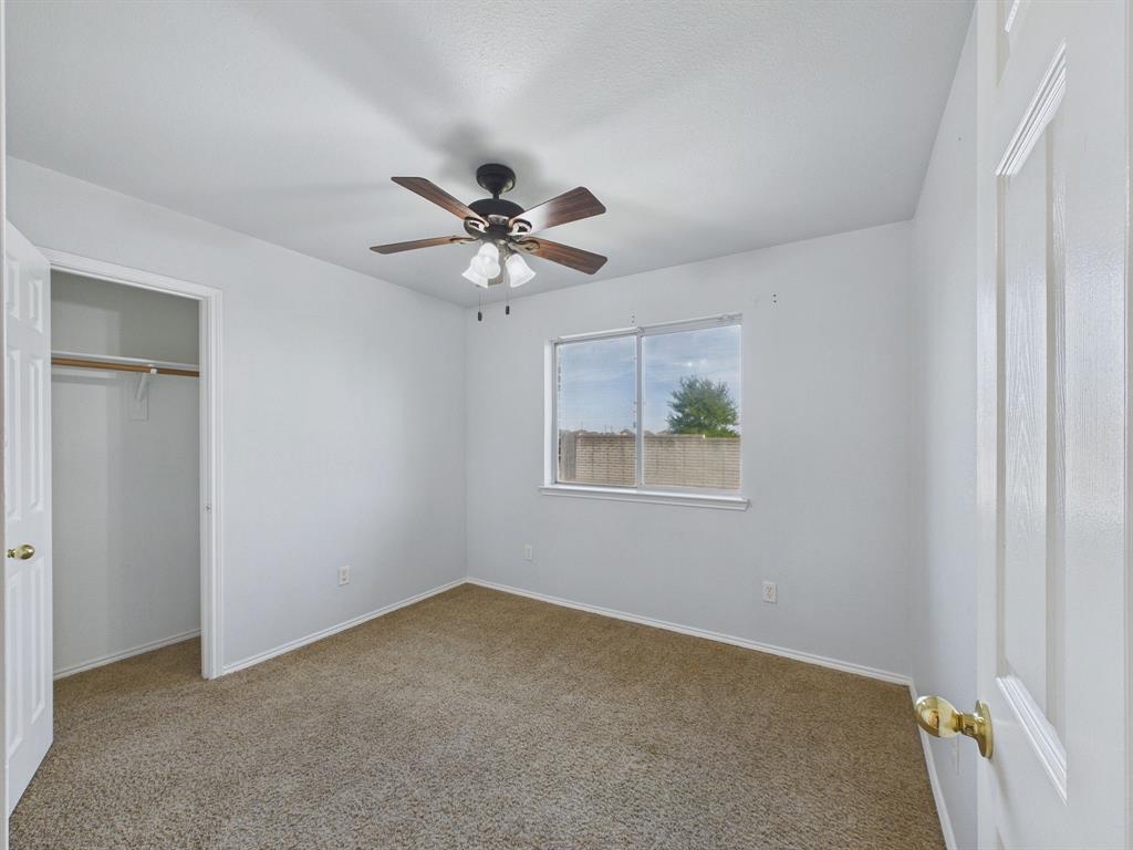 Neutral-toned carpeting, ceiling fan with integrated lighting, slider window, and built-in closet