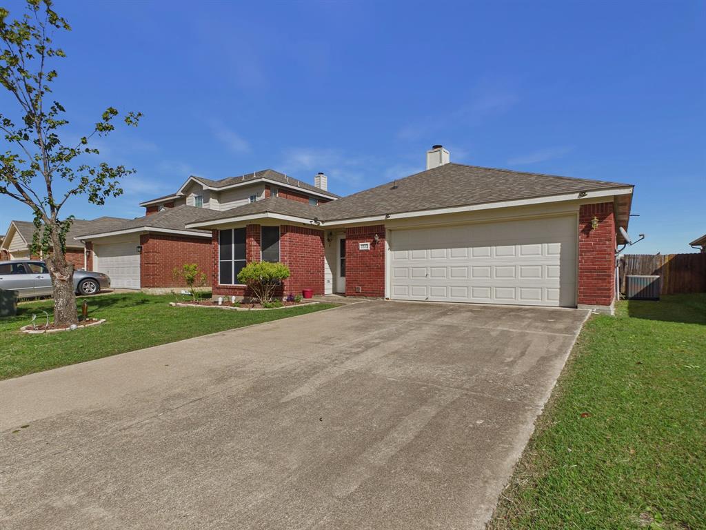 Single-story brick exterior featuring a multi-gable roofline, a two-car garage with a paneled door, and a concrete driveway
