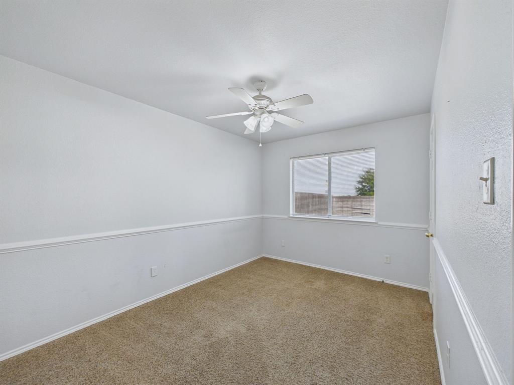 Neutral-toned room featuring neutral carpeting, white wall paneling, and a center-mounted ceiling fan with integrated lighting
