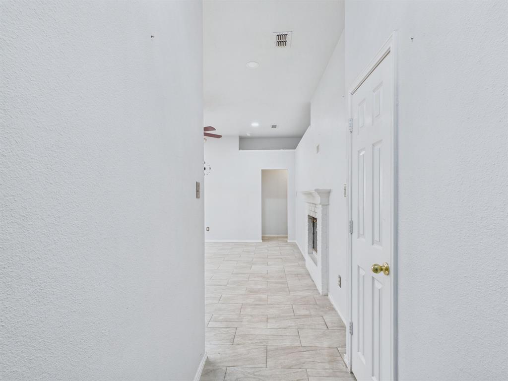 Neutral-toned tile flooring, recessed lighting, and a fireplace with a decorative mantel featuring a classic surround