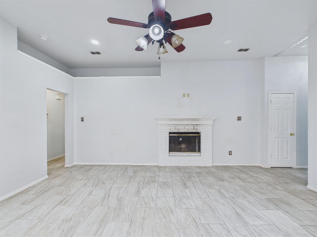 Interior room featuring a fireplace with a white painted brick surround and mantel, wood-finish tile flooring, recessed lighting, and a multi-blade ceiling fan with integrated light fixtures