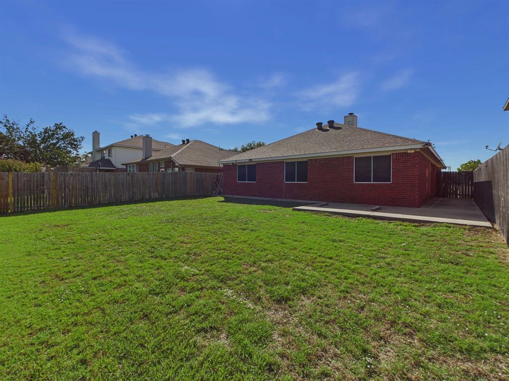 Backyard featuring a red brick exterior, a concrete patio, and a wood privacy fence