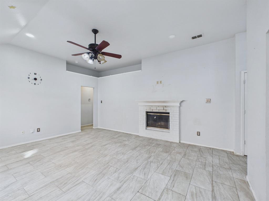 Living space featuring tray ceiling, recessed lighting, tile flooring, and a fireplace with a white brick surround
