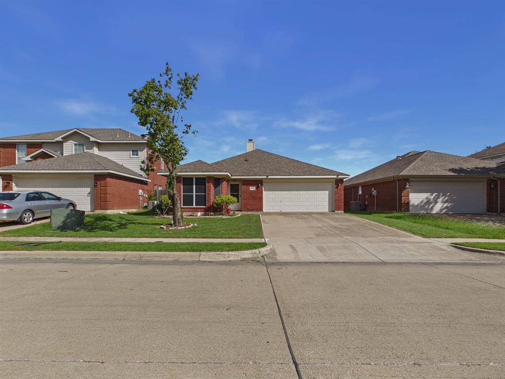 Single-story brick exterior featuring a shingle roof, multi-panel garage door, concrete driveway, and front lawn landscaping