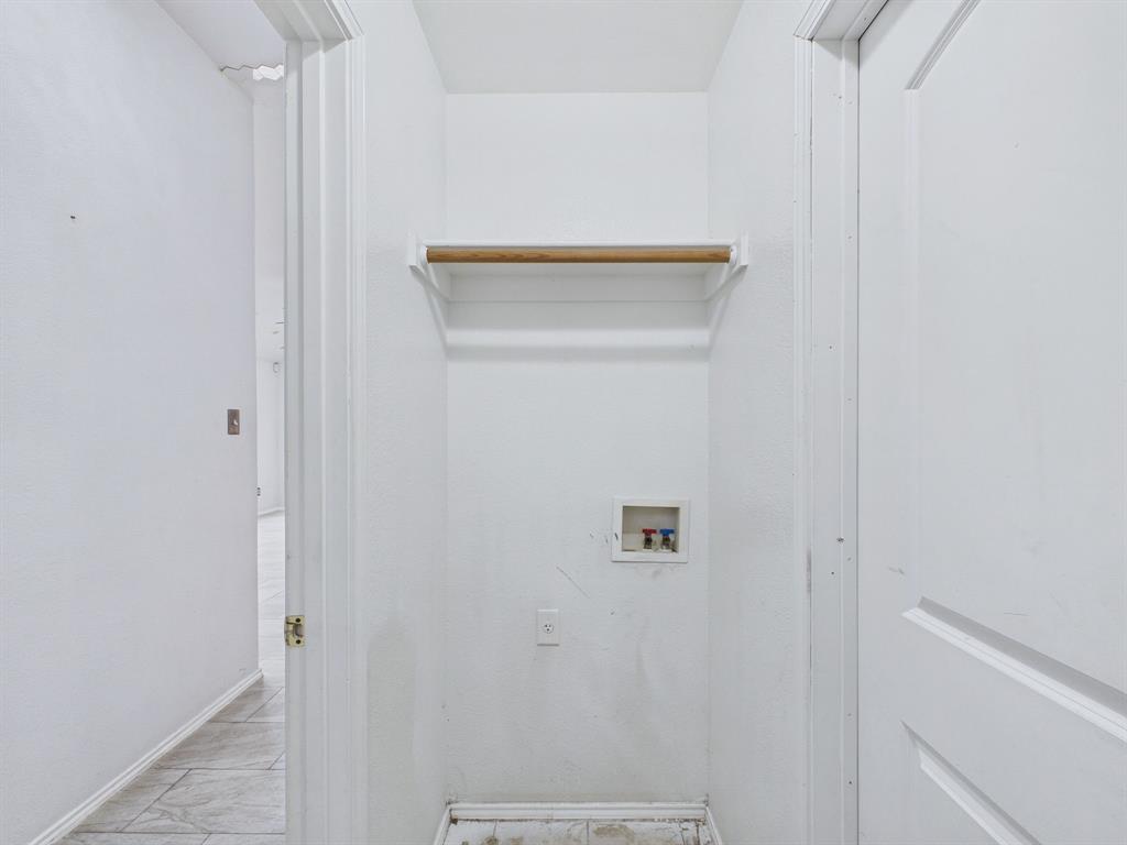 Utility closet featuring a recessed plumbing connection box, electrical outlet, and built-in overhead shelf with integrated garment rod