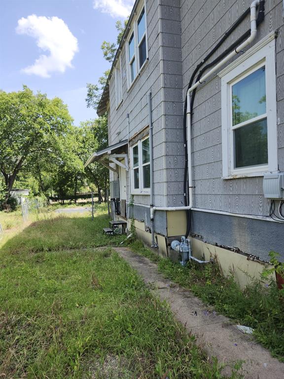 Exterior siding with white-trimmed double-hung windows, concrete walkway, and metal door awning