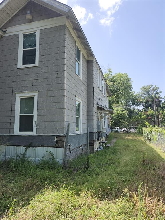 Two-story exterior featuring rectangular siding, double-hung windows with white trim, and an overhanging gable roofline