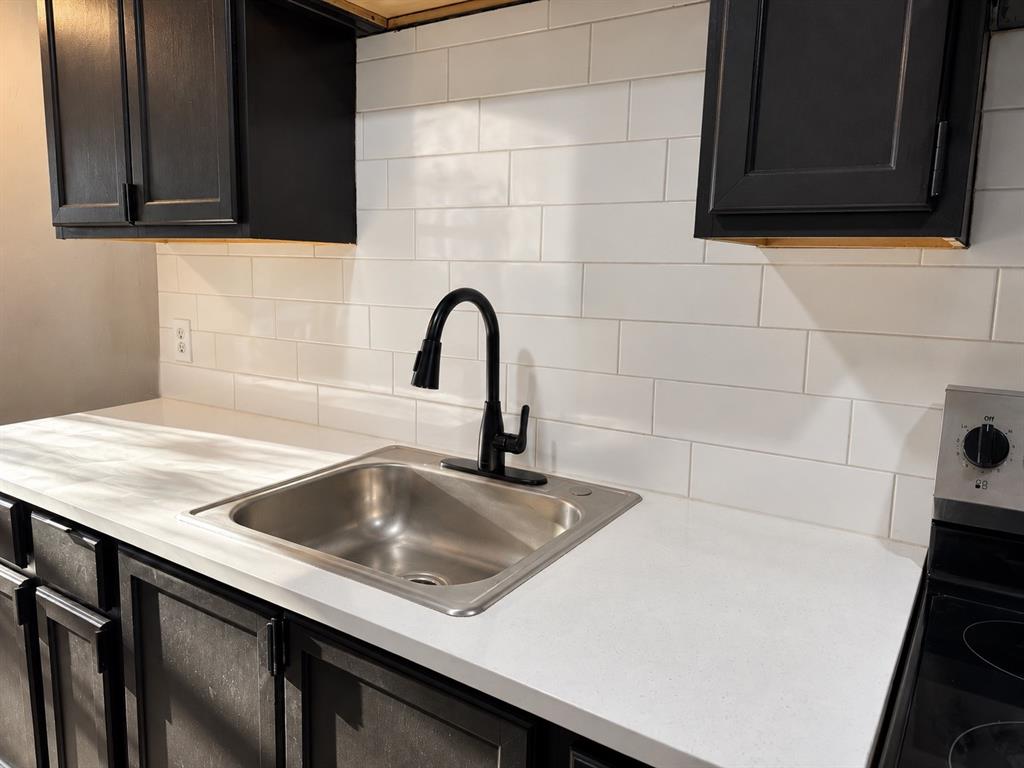 Functional kitchen featuring dark cabinetry, light countertops, and a classic subway tile backsplash.