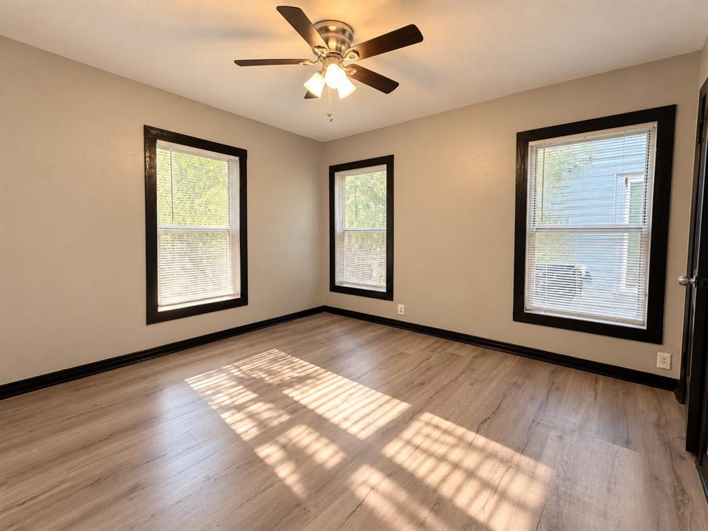 Versatile secondary bedroom with neutral tones and wood-look flooring.