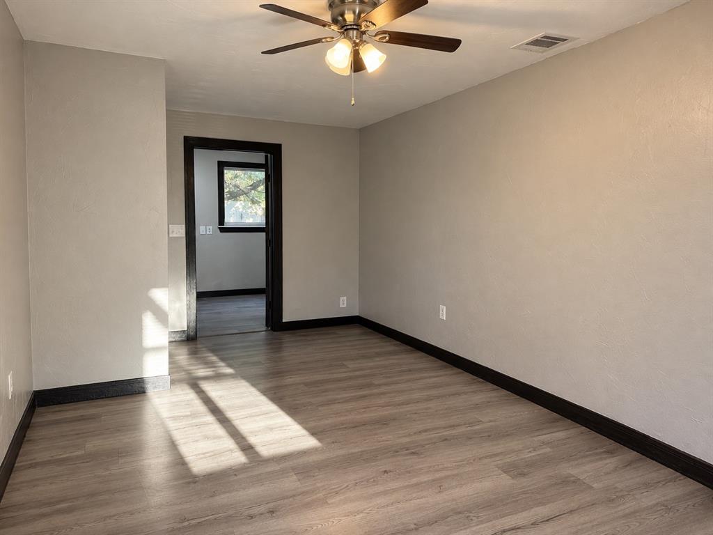 Spacious primary bedroom with neutral finishes and wood-look flooring.
