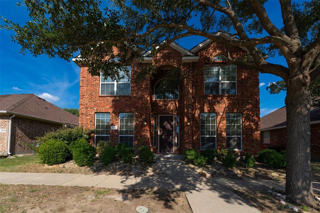 Two-story brick exterior featuring a multi-gabled roofline, arched entryway, and grid-pattern windows