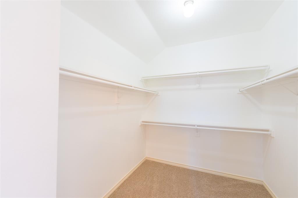 Walk-in closet featuring carpeted flooring, tiered white wire shelving, and overhead lighting