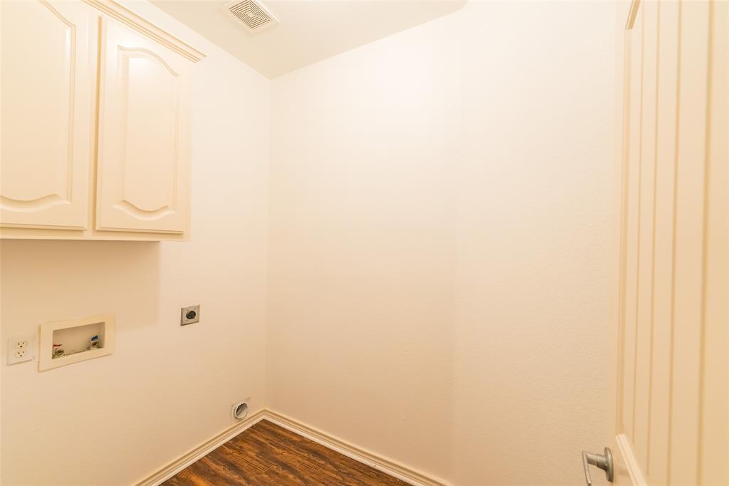 Utility area featuring wall-mounted cabinetry, wood-finish flooring, and dedicated hookups for appliances