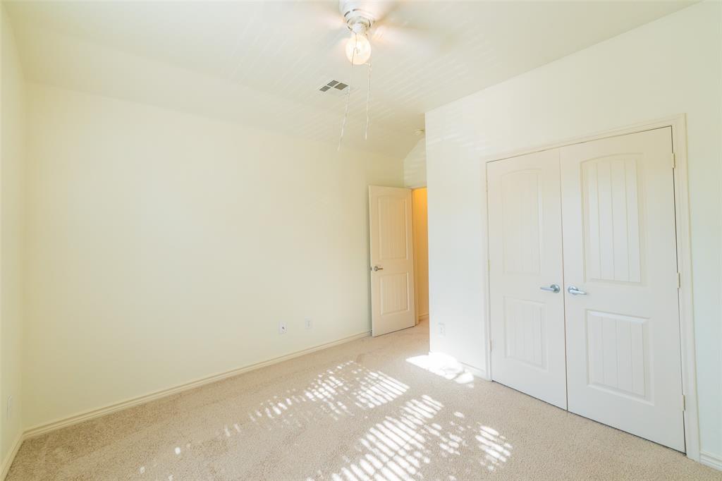 Neutral-toned wall-to-wall carpeting, dual-panel closet doors, single-panel interior door, and a ceiling fan with integrated lighting