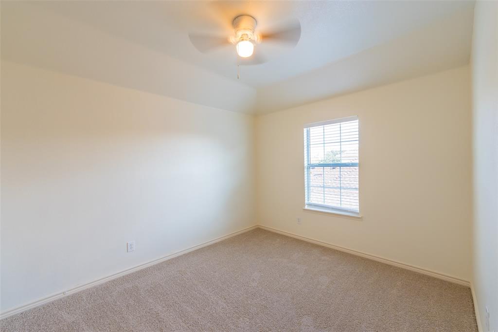 Room featuring neutral wall tones, neutral carpeting, a tray ceiling, and a ceiling-mounted light fixture with a fan