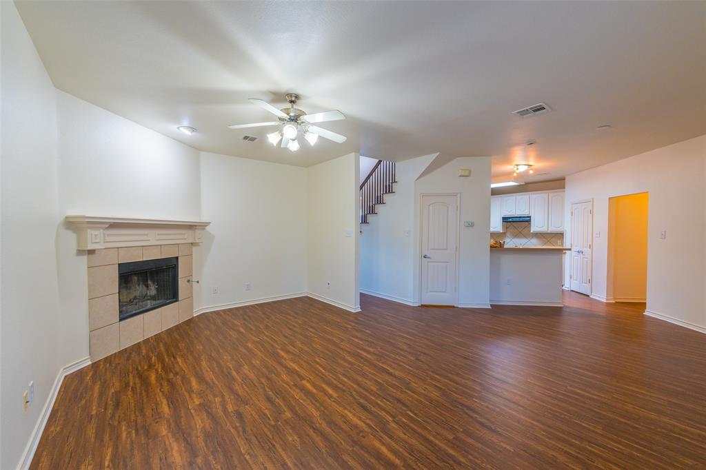 Fireplace featuring a tile surround and mantel, wood-finish flooring, and a multi-light ceiling fan