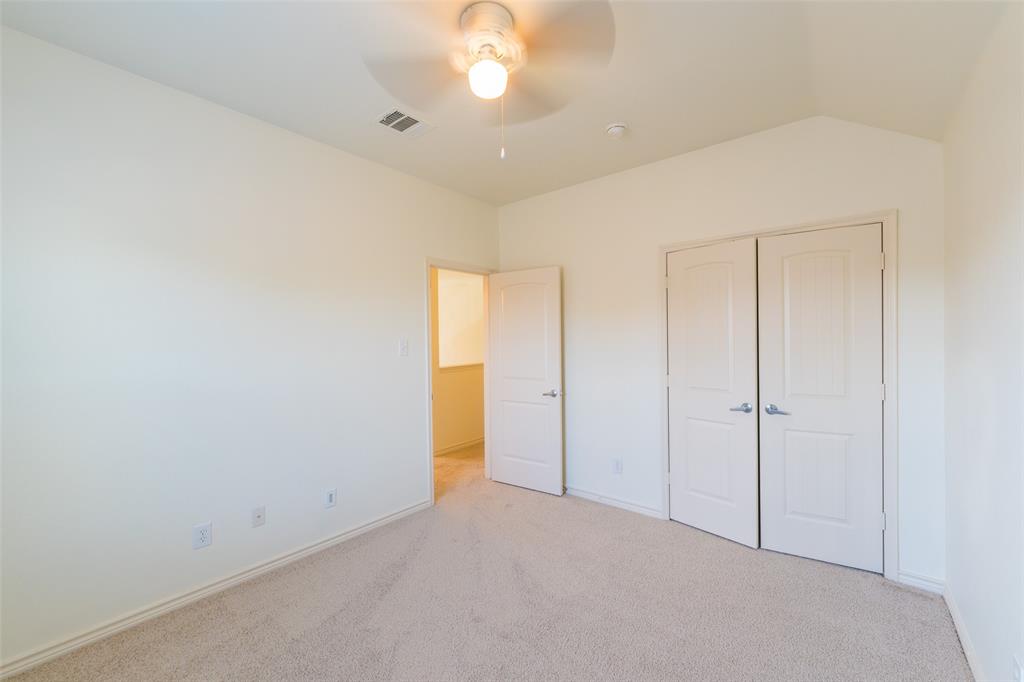 Vaulted ceilings, neutral carpeting, and a double-door closet with paneled detailing, complemented by a ceiling fan with integrated lighting