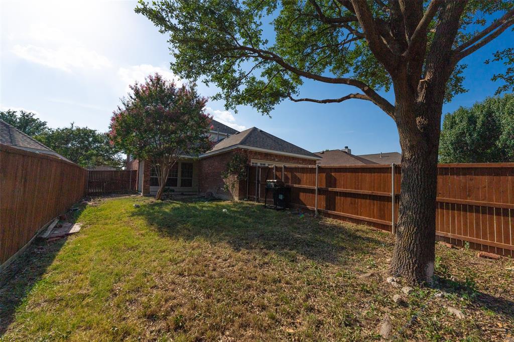 Backyard space featuring a brick exterior, perimeter wood fencing, and mature trees