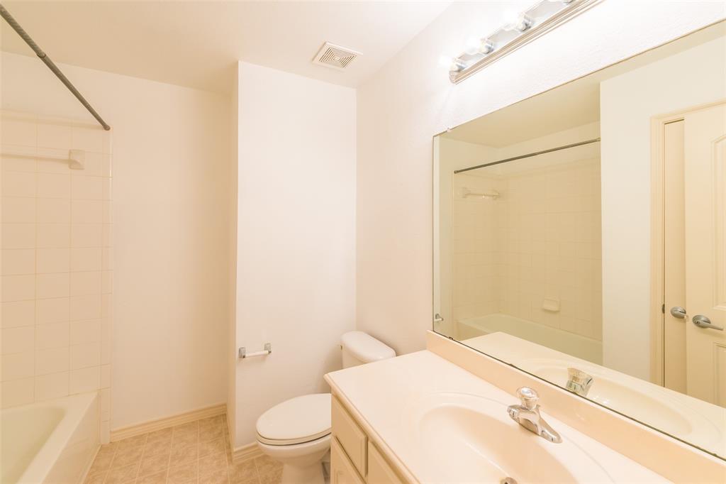 Bathroom featuring a vanity with an integrated sink, expansive wall-mounted mirror, tiered light fixture, and a tub-shower combination with tiled surround