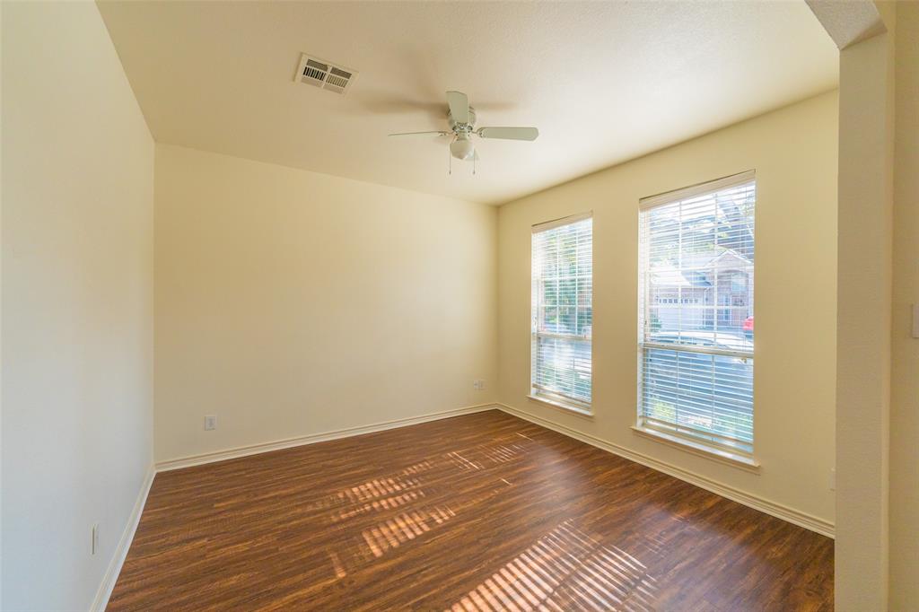 Interior room featuring wood-finish flooring, two large windows, and a ceiling-mounted fan with integrated lighting