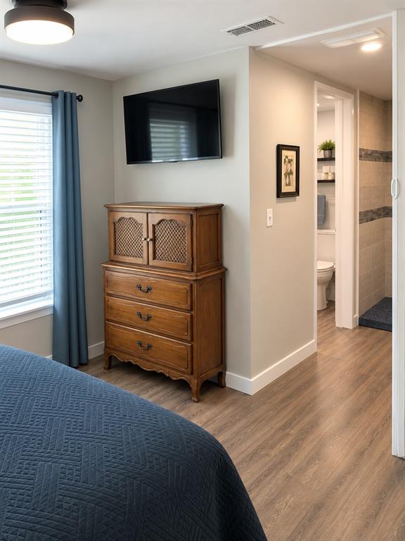 Wood-finish vinyl flooring, neutral wall tones, recessed ceiling lighting, and a walk-through space featuring a tiled shower stall