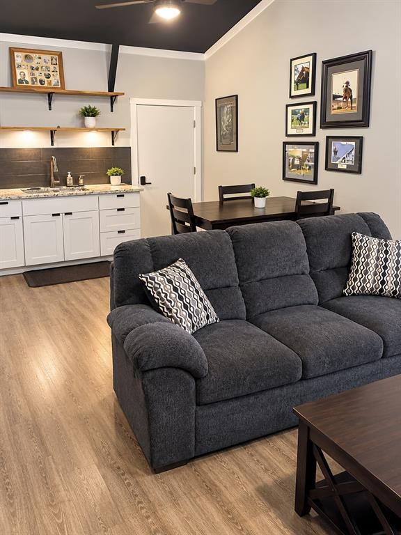 Kitchenette featuring white cabinetry, stone-finish countertops, dark tile backsplash, wood-finish shelving, and vaulted ceilings