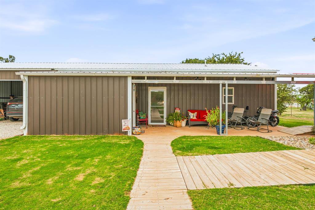 Metal-siding exterior featuring a covered front porch, corrugated metal roof, integrated garage, and wood-plank style walkway