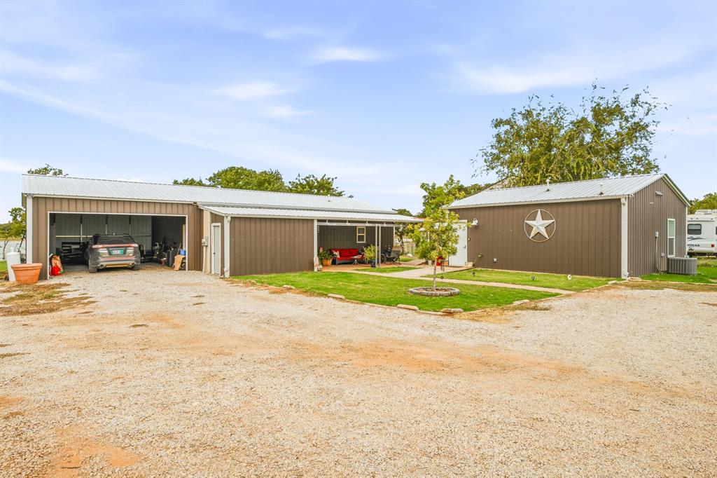 Metal-sided exterior structures featuring a covered front porch, gravel driveway, and attached garage space