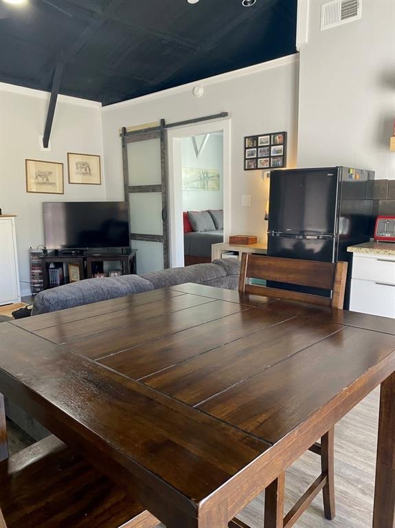 Dark-toned vaulted ceiling, sliding barn door with frosted glass panel, and light-toned wood-finish flooring