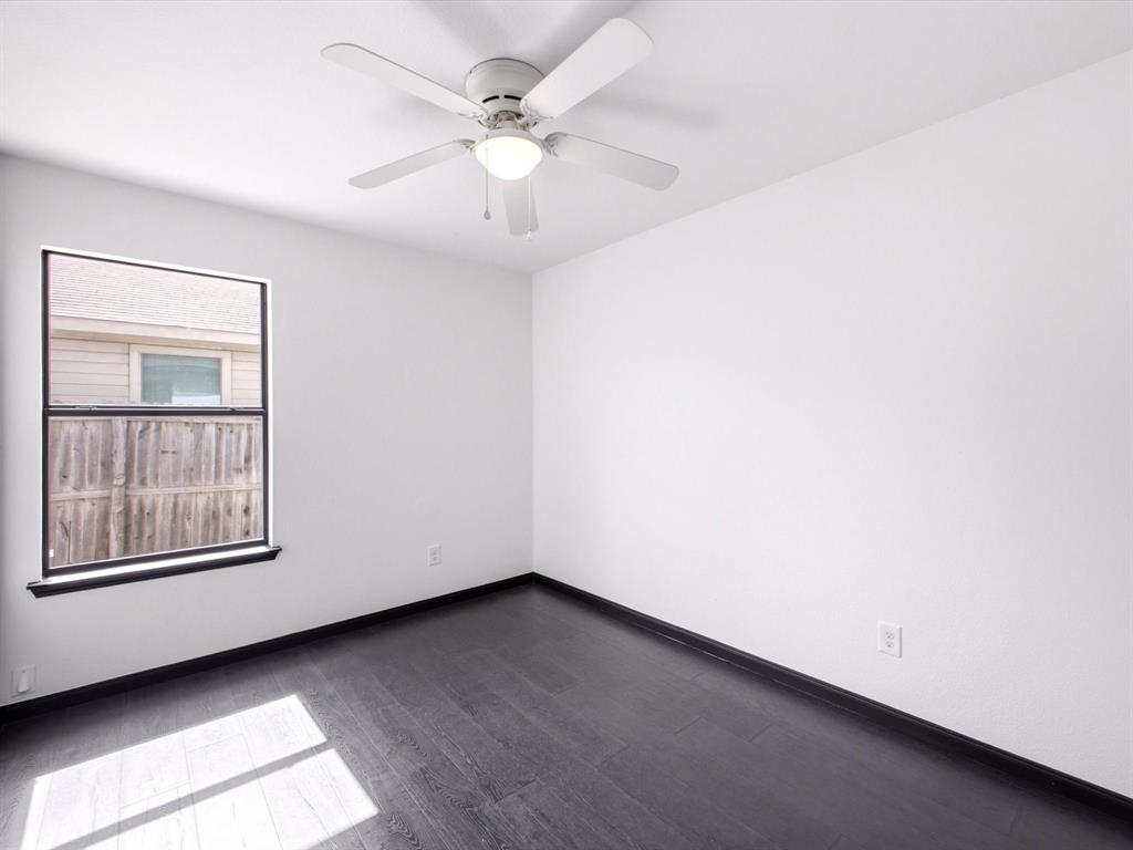 Room featuring dark wood-finish flooring, white walls, a single-hung window, and a ceiling fan with integrated lighting