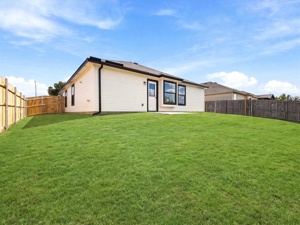 Exterior featuring horizontal siding, dark-framed windows, a dedicated entry door, and a grass-covered backyard enclosed by wood privacy fencing