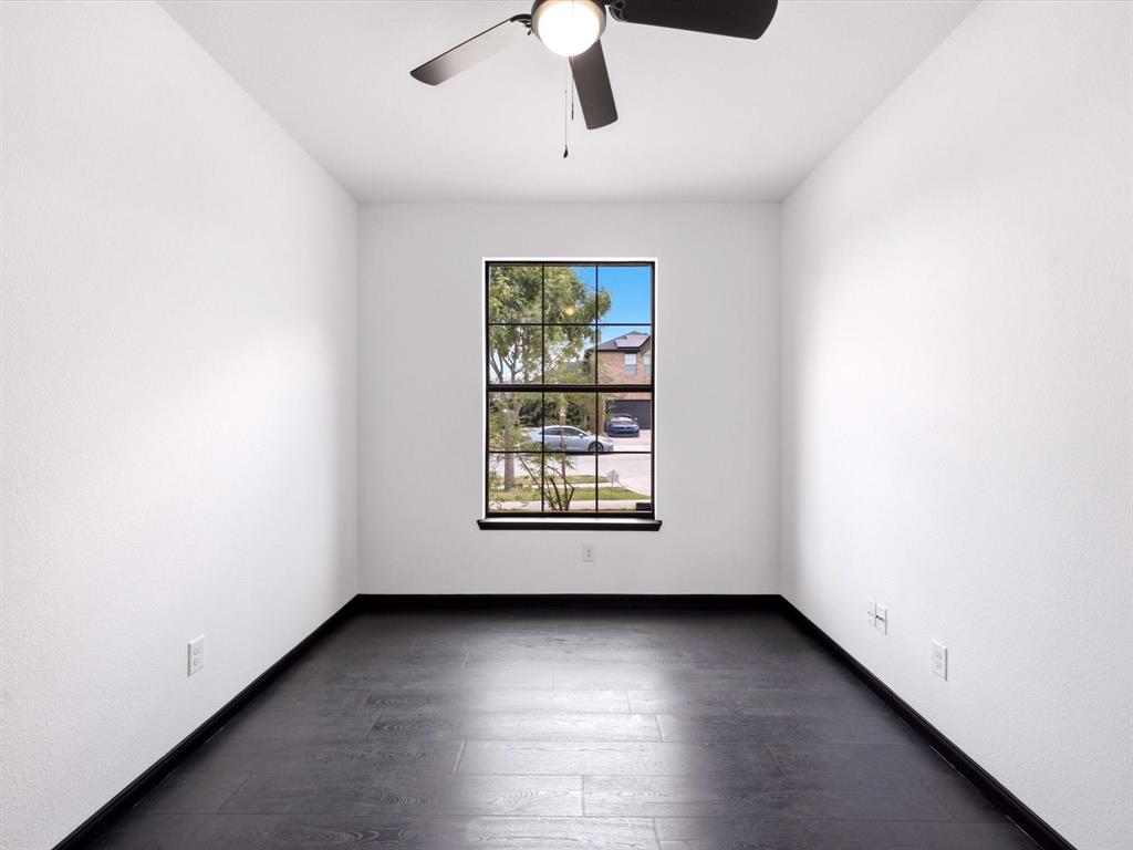 Room featuring wood-finish flooring, dark-framed grid window, and ceiling fan with integrated lighting